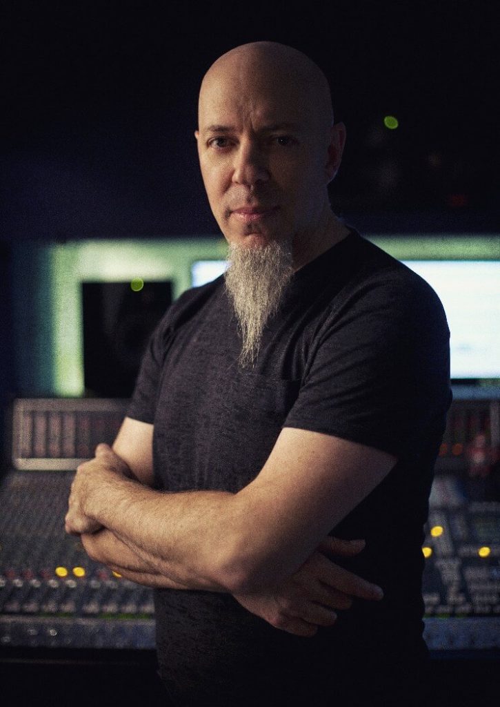 Man with goatee and black shirt standing in front of studio gear.