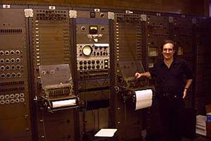 Man standing next to wall of switches.