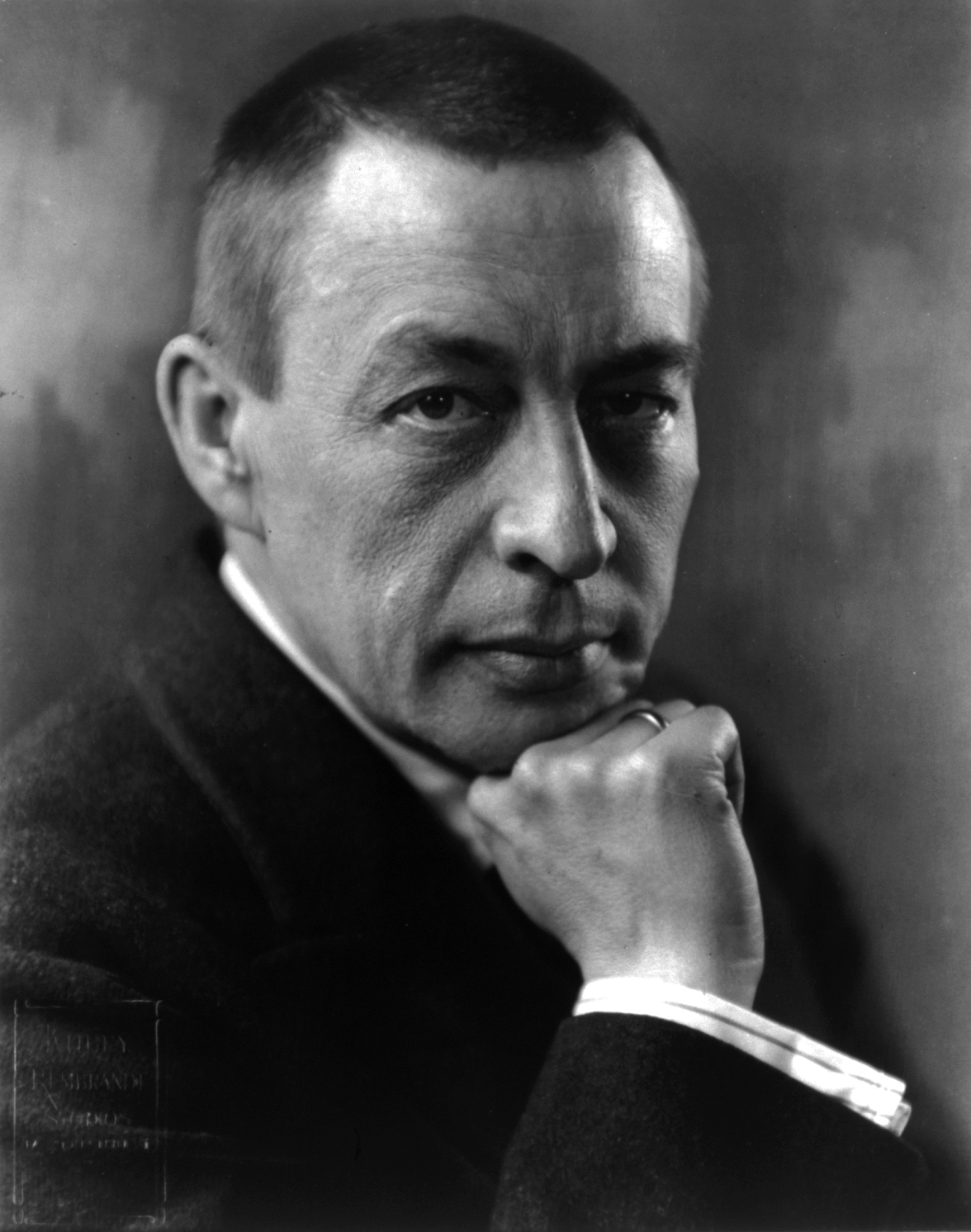 Famous pianists: Sergei Rachmaninoff. Black and white photo of man with buzzed hair with chin on fist.